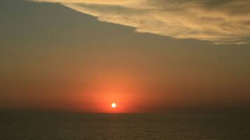 Un coucher de soleil sur une mer calme, avec un horizon dégagé.