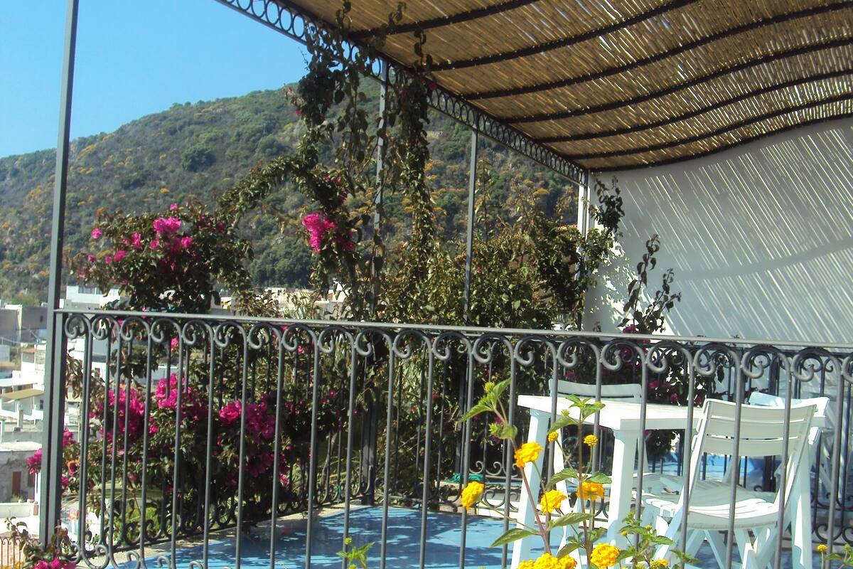 A covered outdoor seating area with metal railings, a table, and chairs.