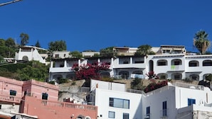 A hillside residential area with white buildings, some with balconies and windows. - Oltremare (Lipari)