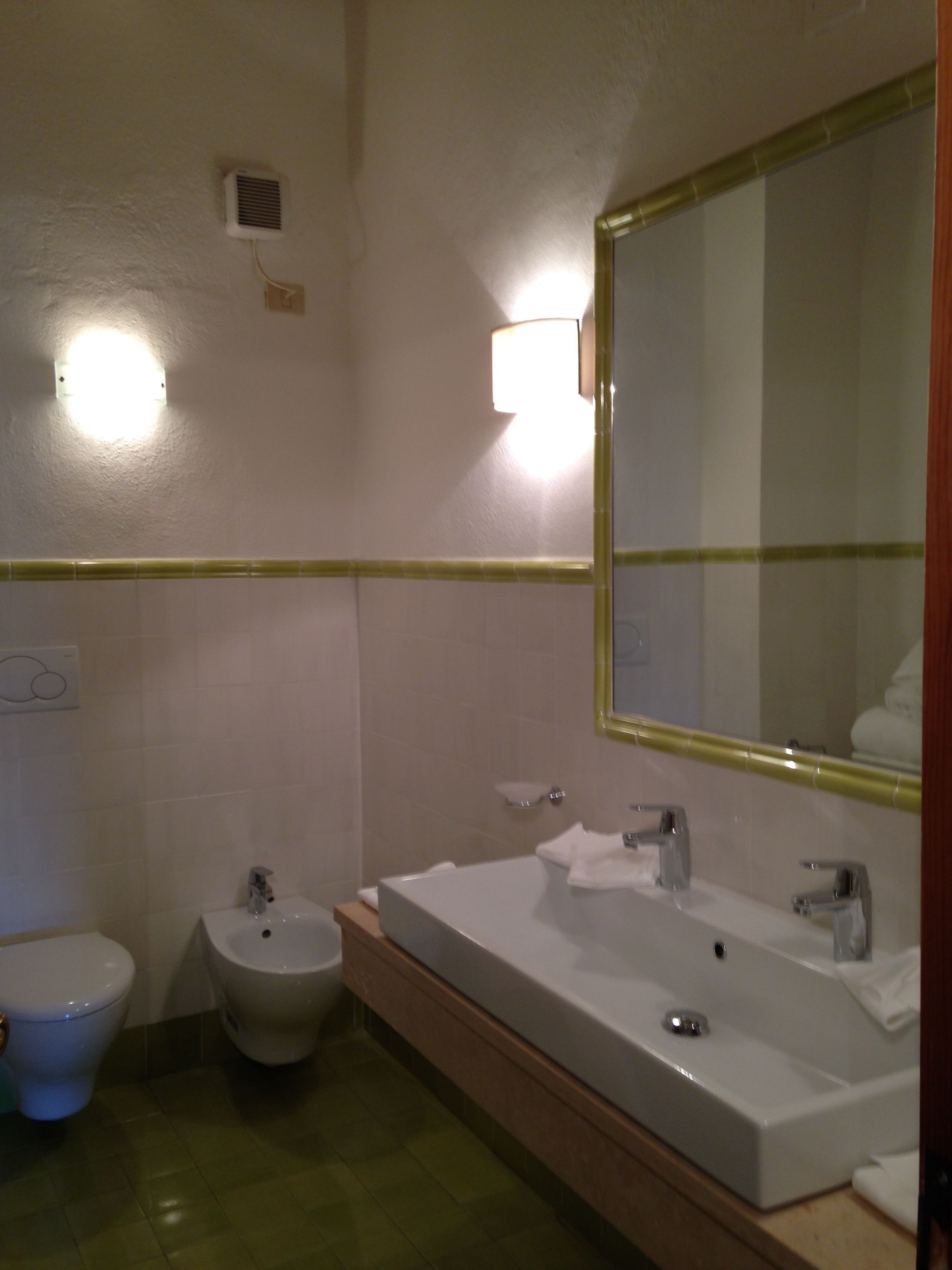Un baño con un espejo grande, un lavabo, un bidé y un inodoro.