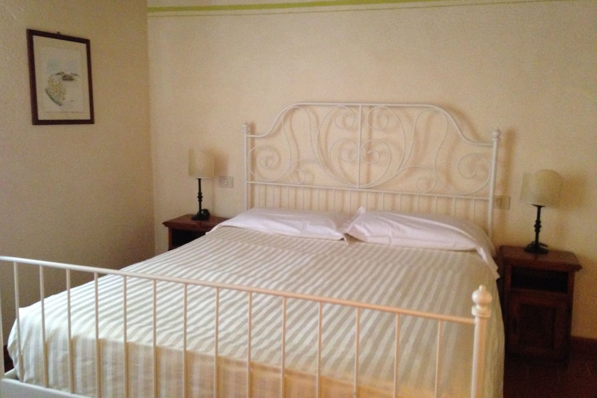 A bed with a metal headboard, two bedside tables with lamps, and a framed picture on the wall.
