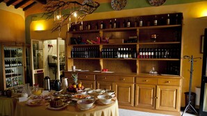 A dining area with a round table set for a meal, surrounded by wooden cabinets stocked with wine bottles. - Fattoria Casabianca (Murlo)