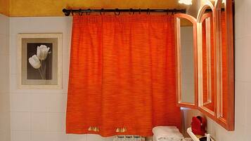 Une salle de bain avec deux lavabos, des toilettes, un bidet, un rideau de douche, un porte-serviettes, un miroir et un tableau encadré au mur.