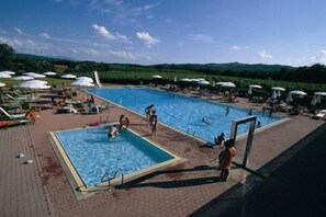 A swimming pool area with multiple pools, lounge chairs, and umbrellas. - Fattoria Casabianca (Murlo)