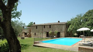 A stone building with a swimming pool, surrounded by grass and trees. - Fattoria Casabianca (Murlo)