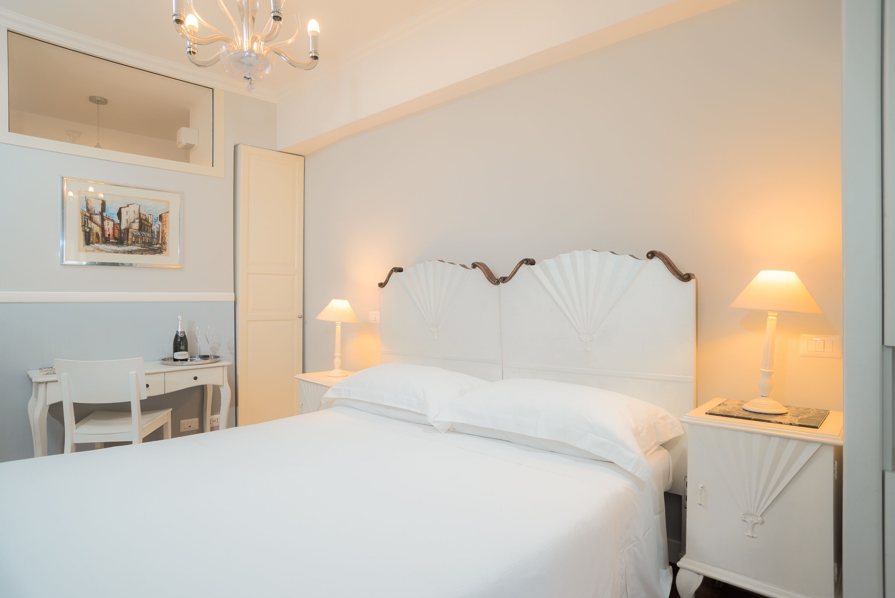 A neatly arranged hotel room with a large bed, a desk, and two bedside lamps.
