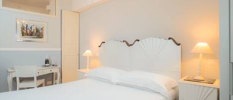 A neatly arranged hotel room with a large bed, a desk, and two bedside lamps.