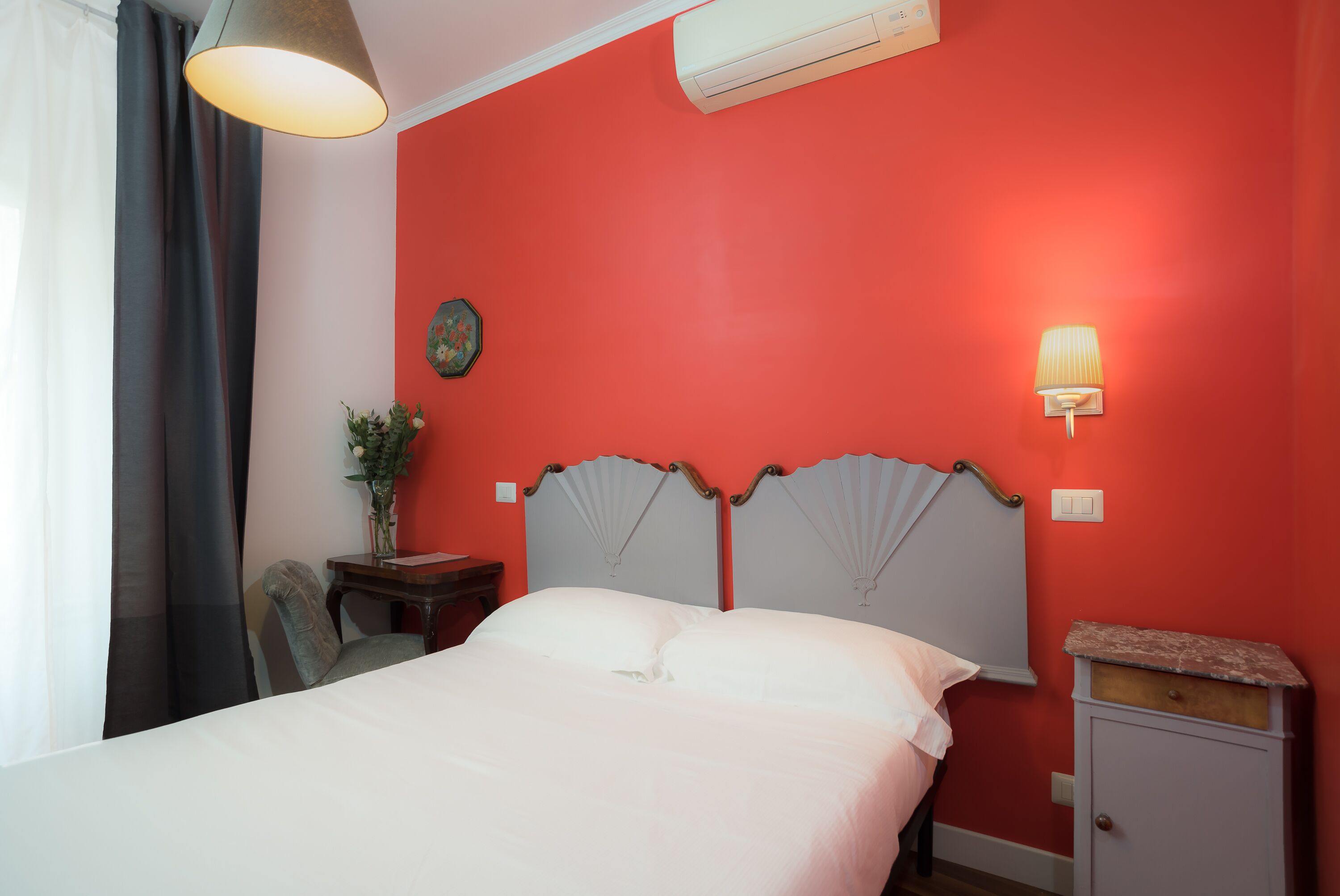 A room with a bed, a nightstand, a lamp, and an air conditioning unit.