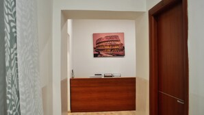 En receptionsdisk med et indrammet billede af Colosseum, en træreception og en trädør.