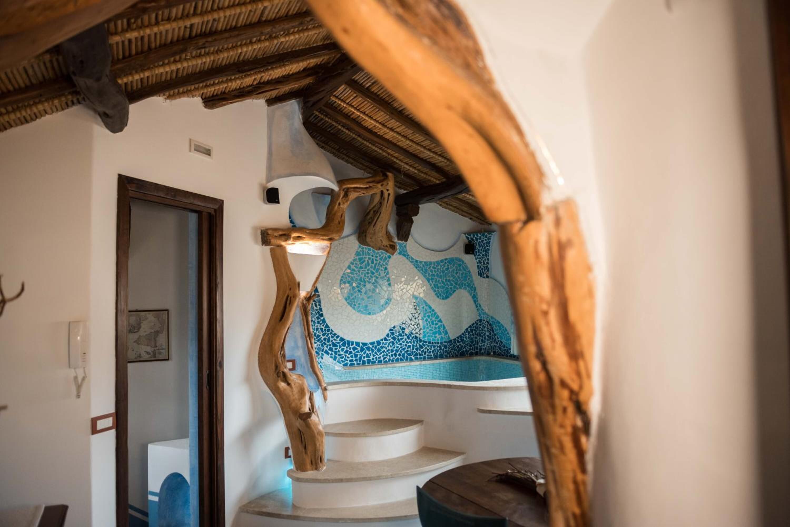 Un escalier avec une rampe en bois et un mur décoré de mosaïques.