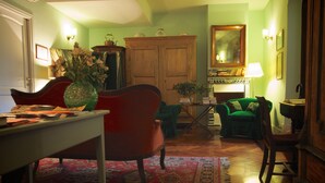 Een gezellige woonkamer met een rode fauteuil, een groene fauteuil en een houten kast.