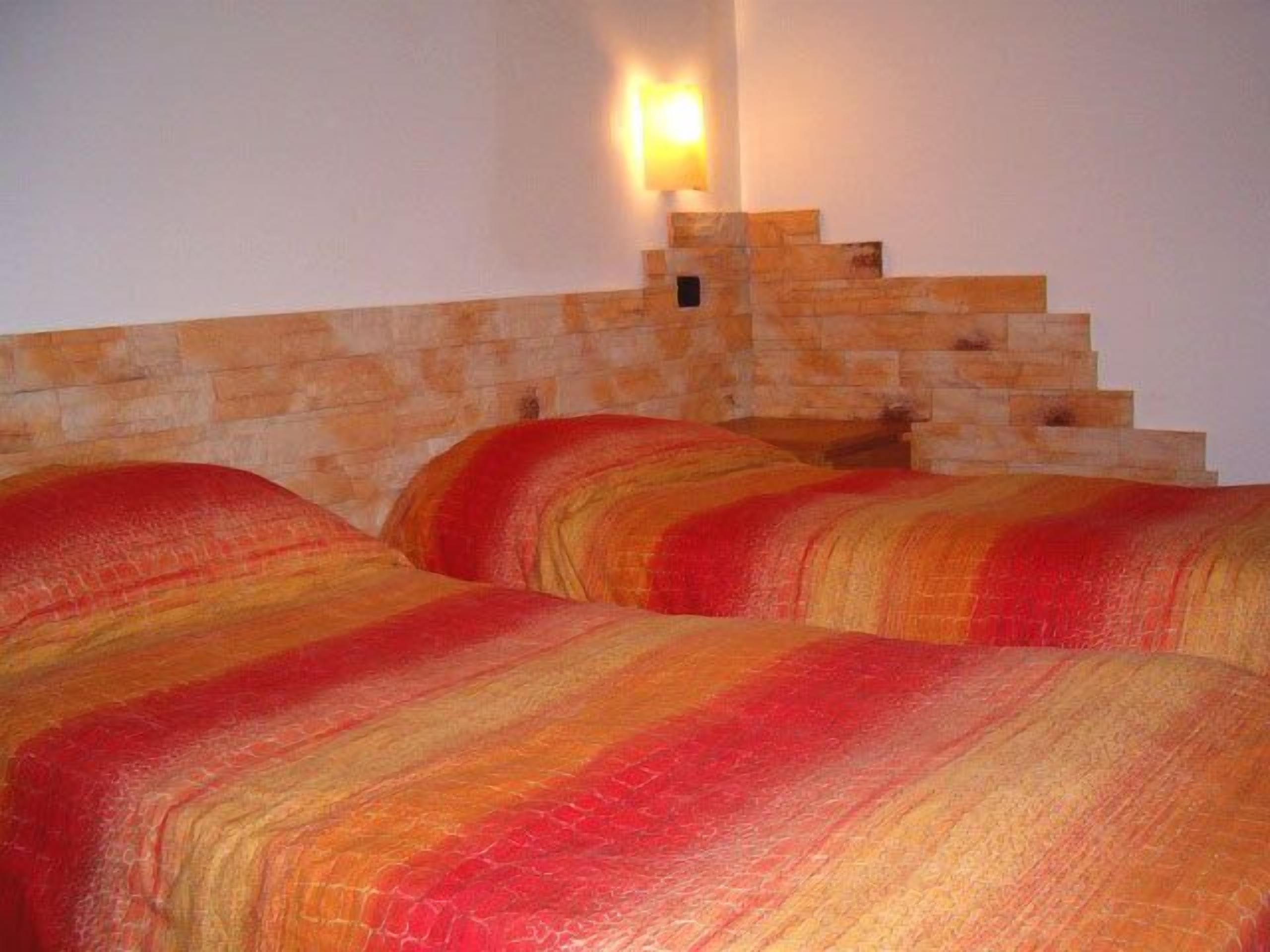 A room with a stone headboard and a wall-mounted light fixture.