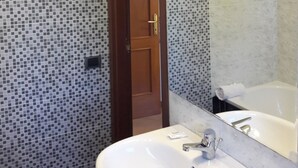 A bathroom with mosaic tile walls, a white sink, a mirror, and a shower area. - Nuova Fiera Aparthouse (Rome)