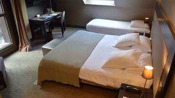 A hotel room with a large bed, a desk, a chair, and a TV.