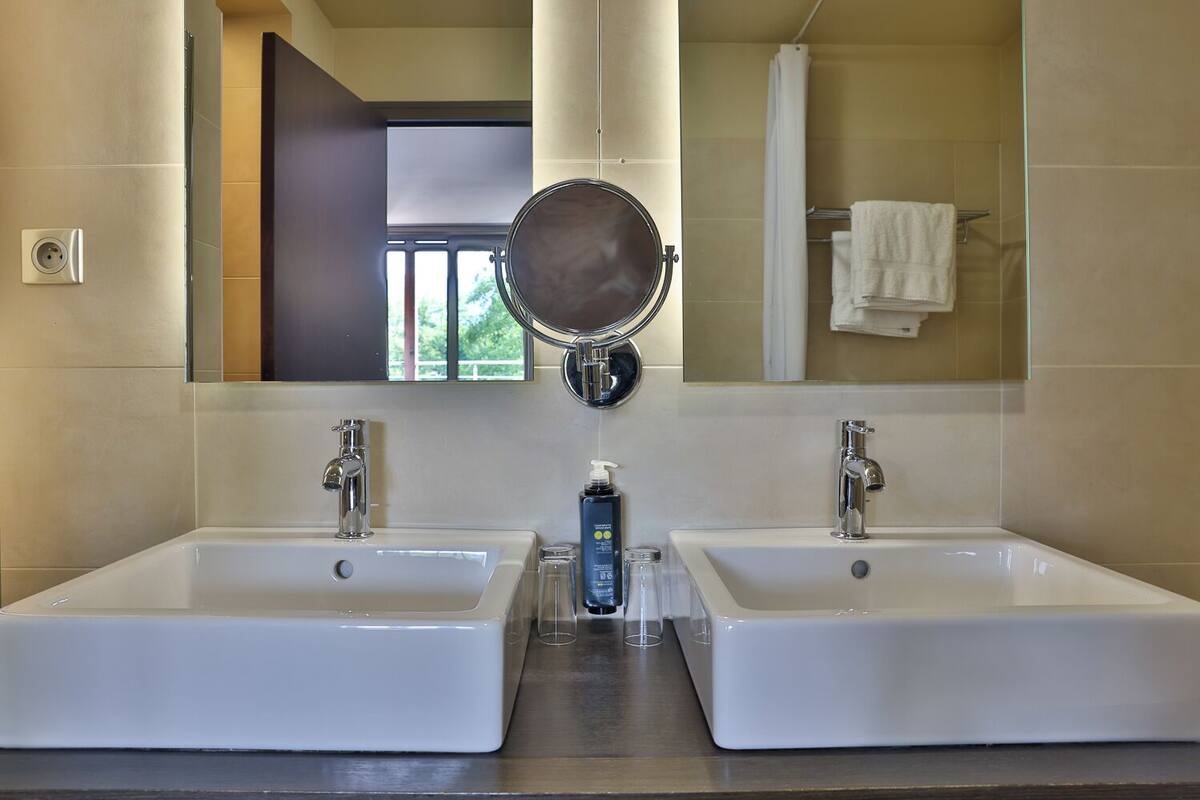 A bathroom with two sinks, a mirror, and a shower.