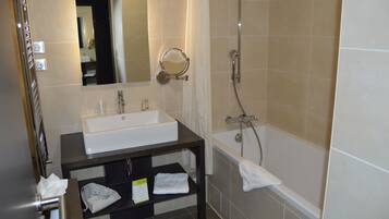 A bathroom with a sink, mirror, shower, and a towel rack.