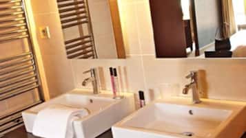 Un bagno moderno con due lavandini, un porta asciugamani e uno specchio.