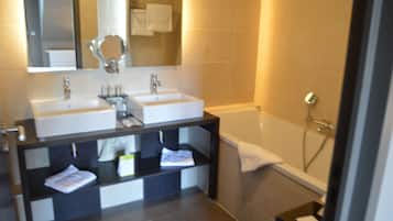 Un baño moderno con dos lavamanos, un espejo, una bañera y una ducha.