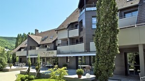 A modern hotel with a restaurant named "LES ARVES" on the ground floor, outdoor seating, and a landscaped garden. - Hôtel les Rives (Guebwiller)