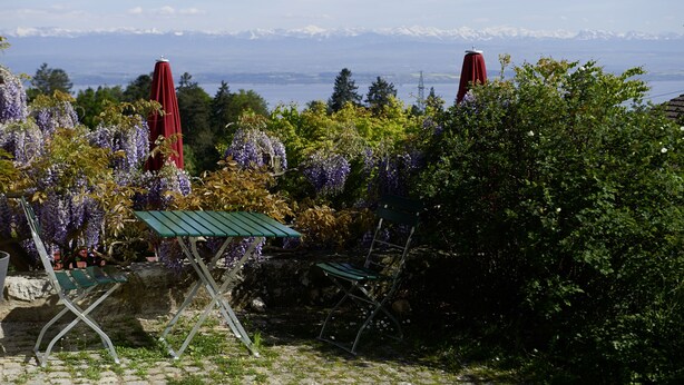A garden with a view of mountains, a table, and two chairs. - EcoHotel L'Aubier (Rochefort)