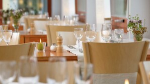 A restaurant setting with tables set for dining, including plates, cutlery, and glasses. - EcoHotel L'Aubier (Rochefort)