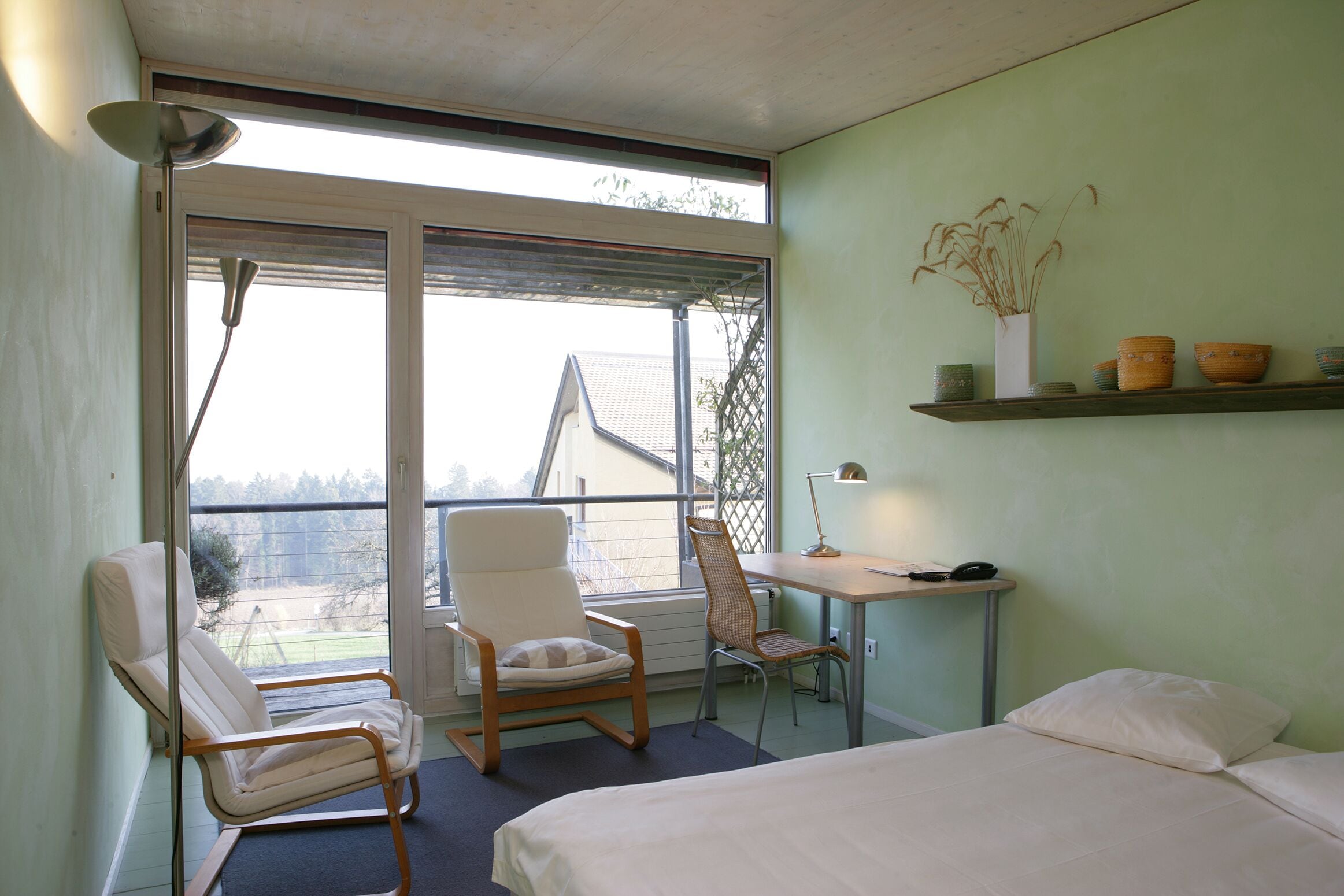 Une pièce comprenant un lit, un bureau, une chaise et une fenêtre.