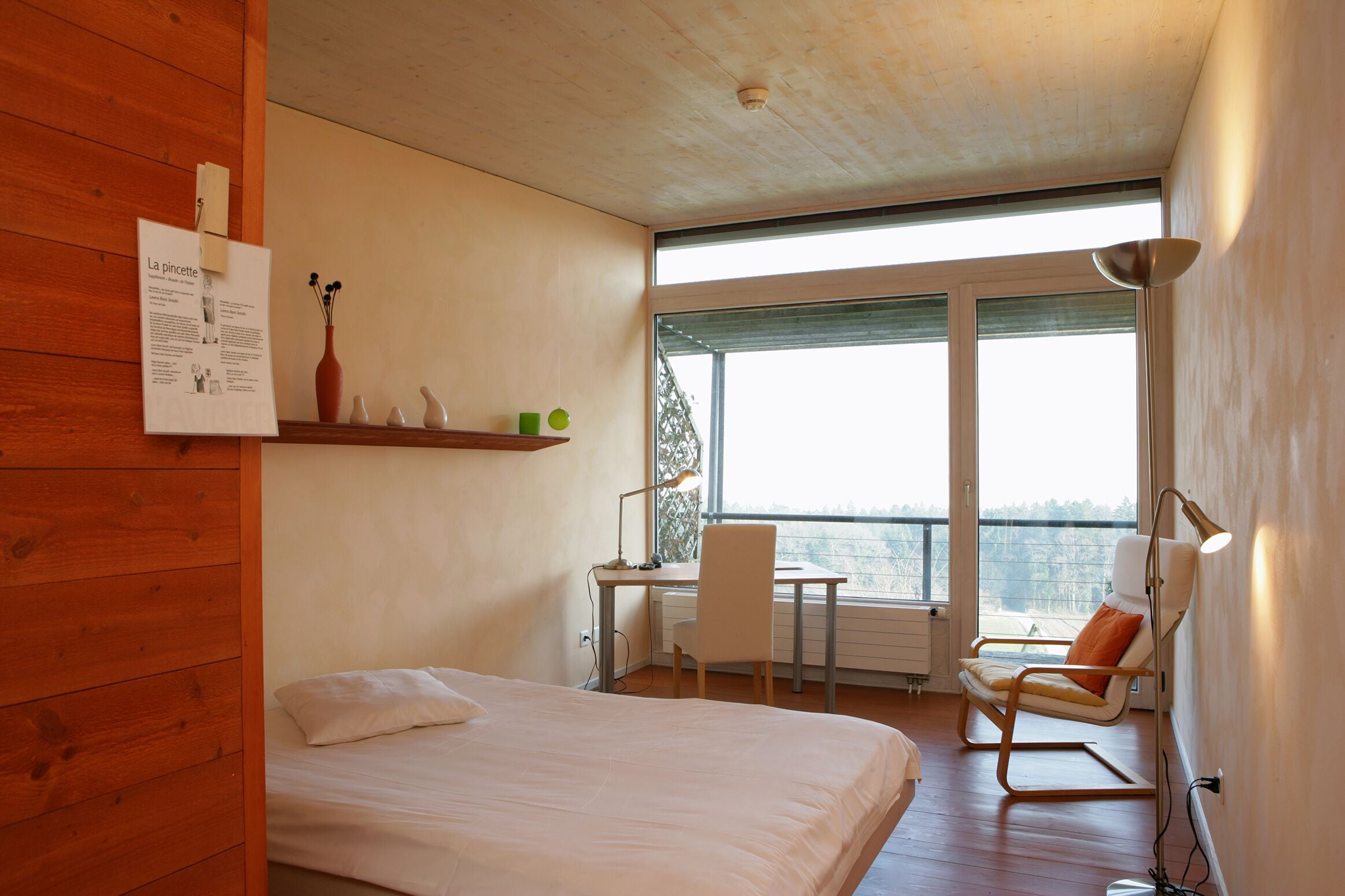 Ein Schlafzimmer mit Bett, Schreibtisch, Stuhl und Blick auf ein Gewässer.
