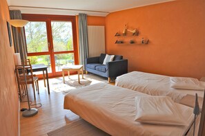 Una habitación de hotel con dos camas, un sofá, una mesa y una silla.