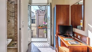 A hotel room with a shower, a wooden desk with a TV, and a view of the outside balcony. - Hotel Katty (Rome)
