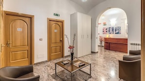 Una hall con porte in legno, una reception, un pavimento in marmo e un lampadario.