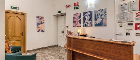 A reception area with a wooden desk, teal chairs, marble flooring, and abstract art on the walls.