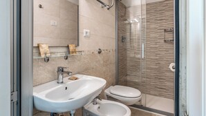 Un bagno moderno con lavandino, servizi igienici e cabina doccia in vetro.