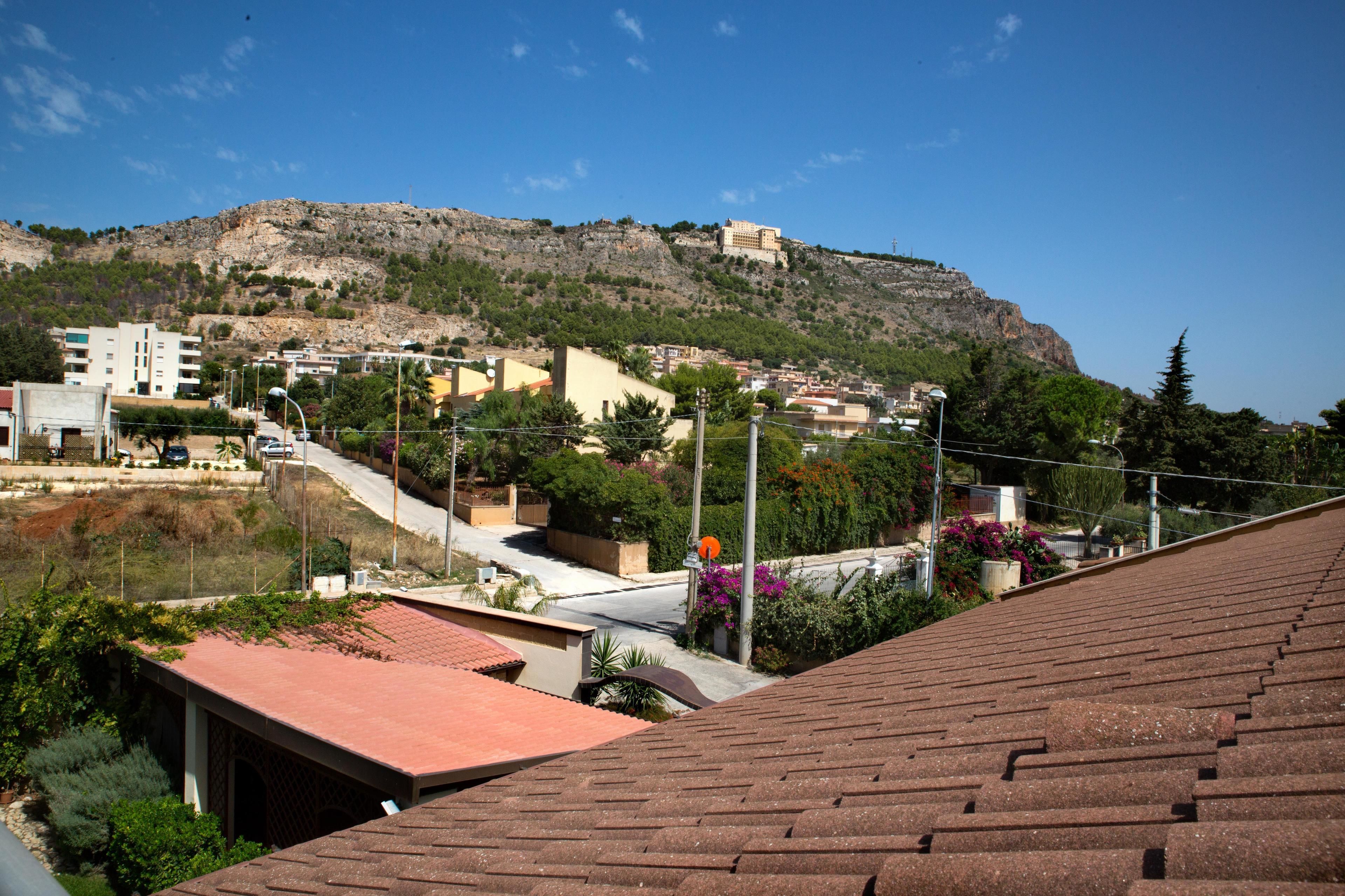 Une ville située sur une colline, avec des bâtiments, une route et une structure imposante qui se dresse au sommet de la colline.