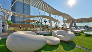 A modern outdoor lounge area with unique seating and a clear view of a tall building in the background. - INTERNATIONAL Hotel Casino & Tower Suites (Golden Sands)