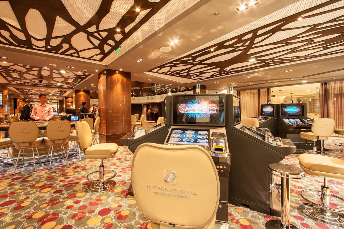 Un espace de casino comprenant des tables de jeu, des chaises et des machines à sous.