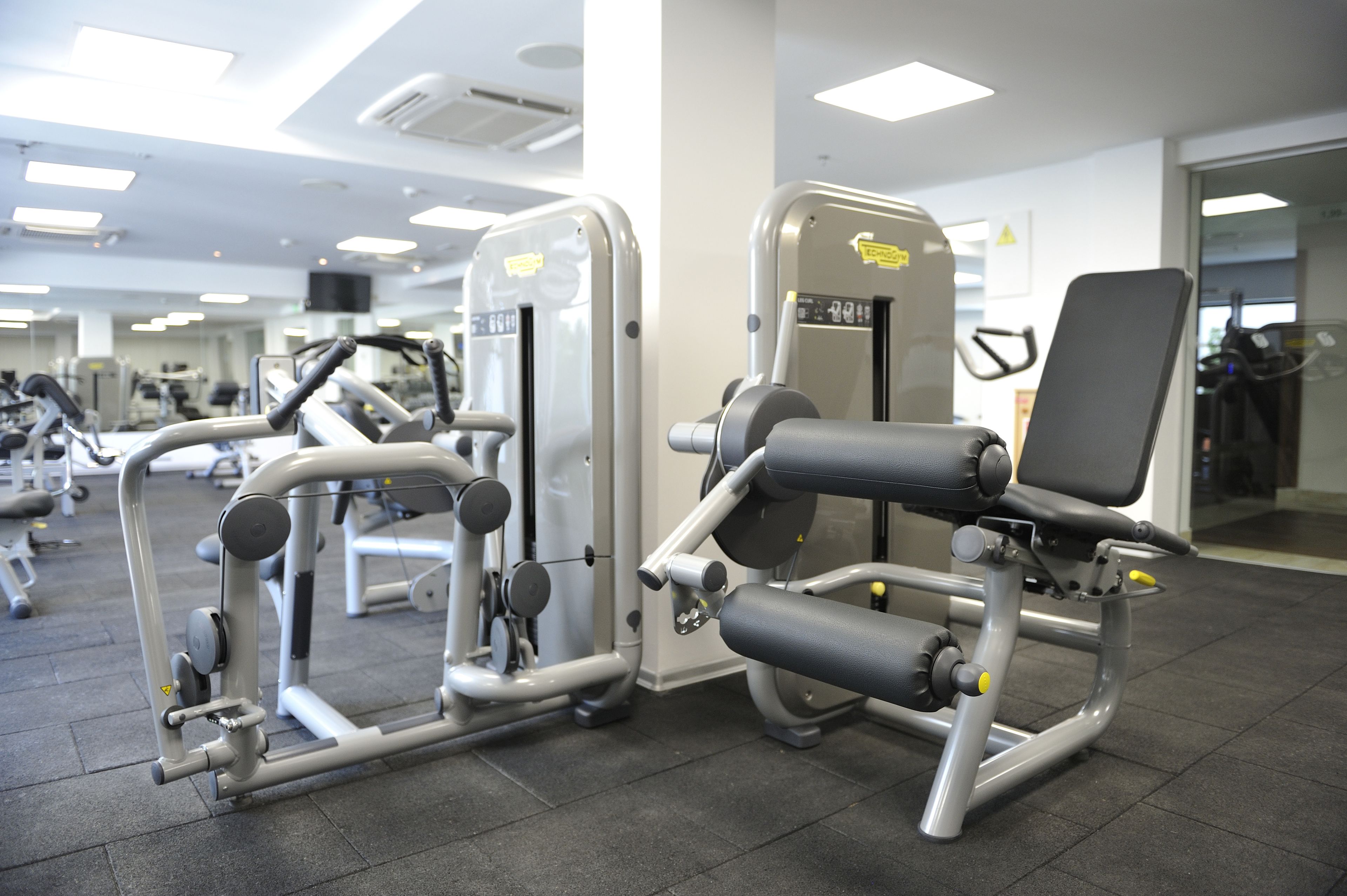 A gym with various exercise machines, including a leg press and a chest press.