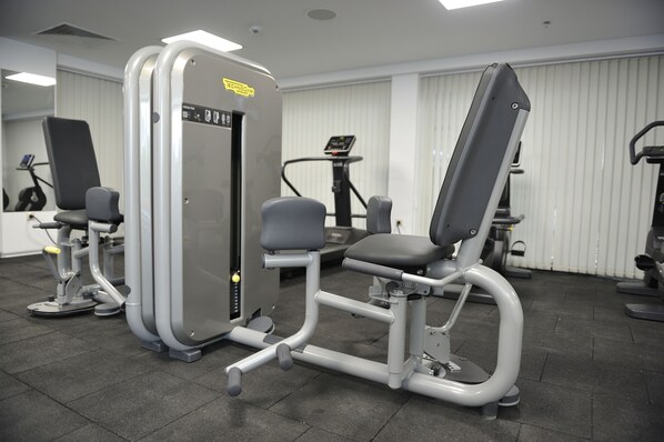 Un gimnasio con equipo de ejercicio, incluyendo una máquina para piernas y un banco de pesas.