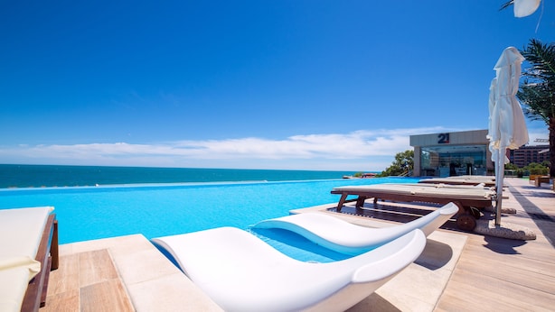 A poolside area with lounge chairs and umbrellas, overlooking a clear blue ocean. - INTERNATIONAL Hotel Casino & Tower Suites (Golden Sands)