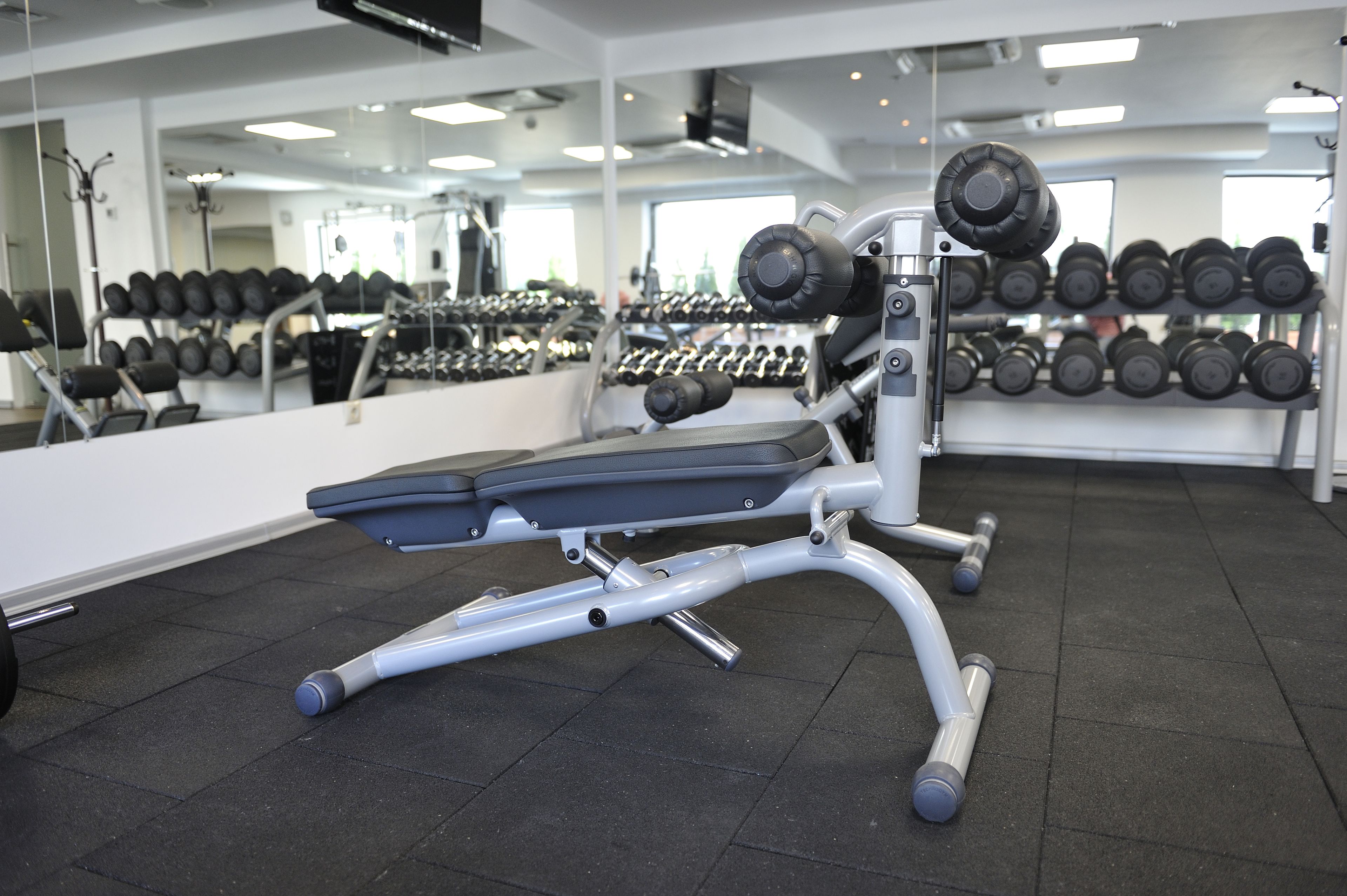 Une salle de sport équipée d’un banc de développé couché, d’haltères et d’un miroir.