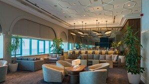 A spacious lounge area with multiple seating arrangements, a bar with a variety of bottles, and large windows offering views. - INTERNATIONAL Hotel Casino & Tower Suites (Golden Sands)