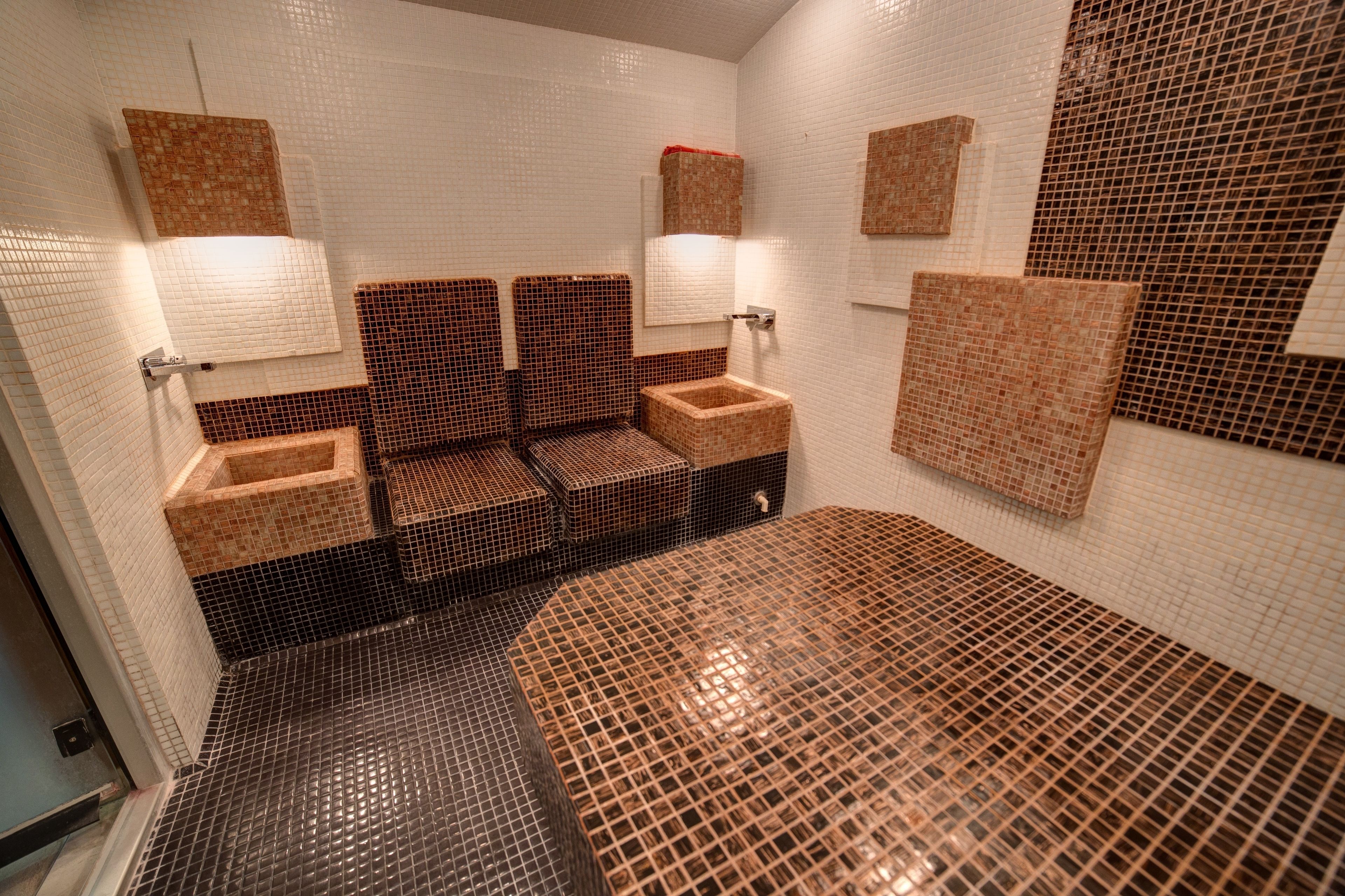 A bathroom with tiled walls, a sink, and a mirror.
