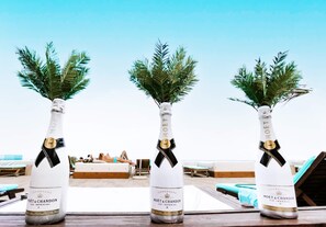 Trois bouteilles de champagne Moët & Chandon Ice Impérial, posées sur une table en bois dans un complexe hôtelier en bord de mer.