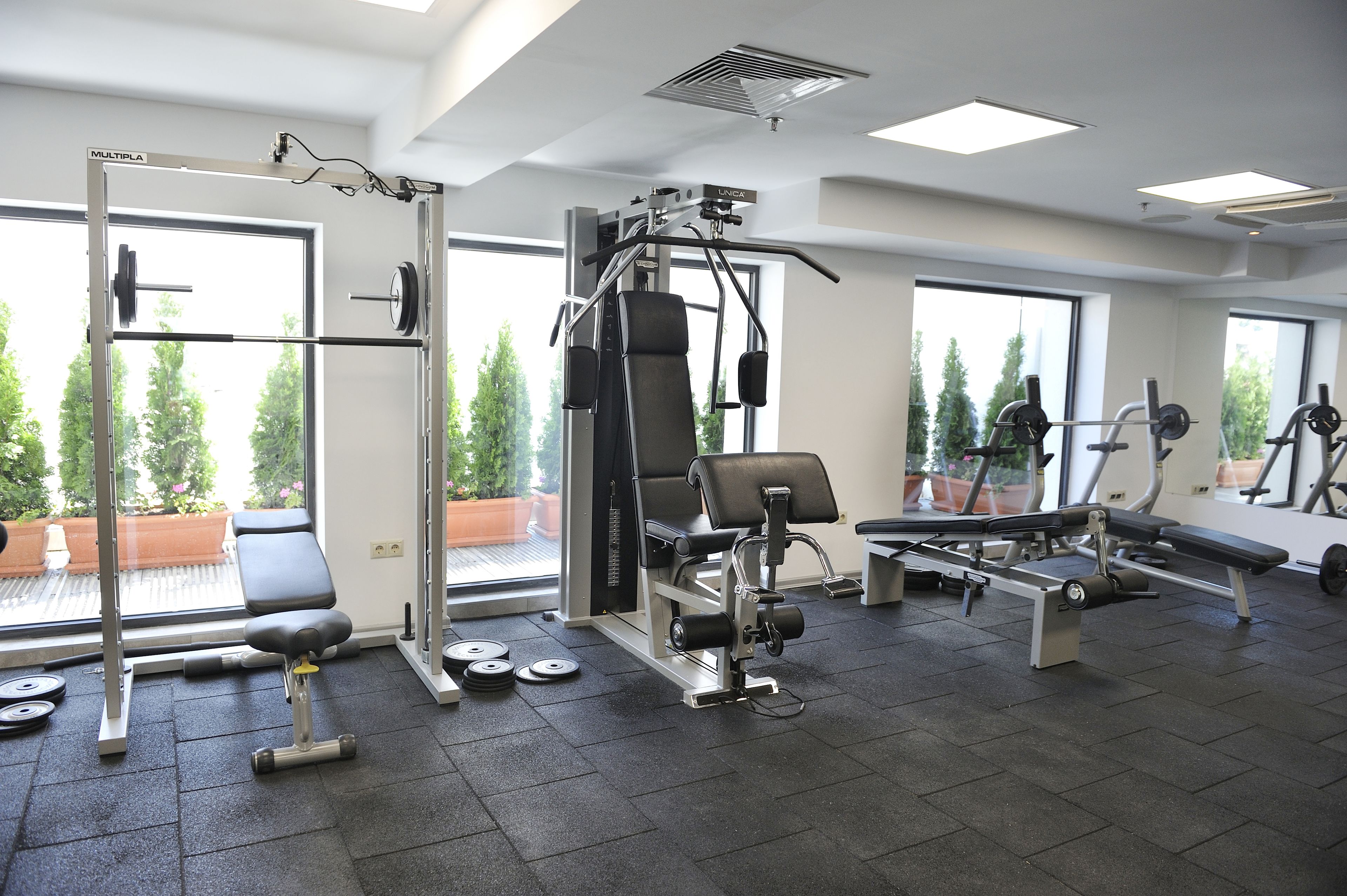 Un gimnasio con equipo de levantamiento de pesas, una banca y mancuernas.