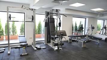 Un gimnasio con equipo de levantamiento de pesas, una banca y mancuernas.