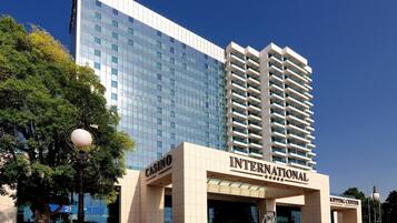 Un hotel moderno con un llamativo letrero de casino, un centro comercial y un edificio alto con ventanas reflectantes.