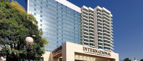 Un hotel moderno con un llamativo letrero de casino, un centro comercial y un edificio alto con ventanas reflectantes.