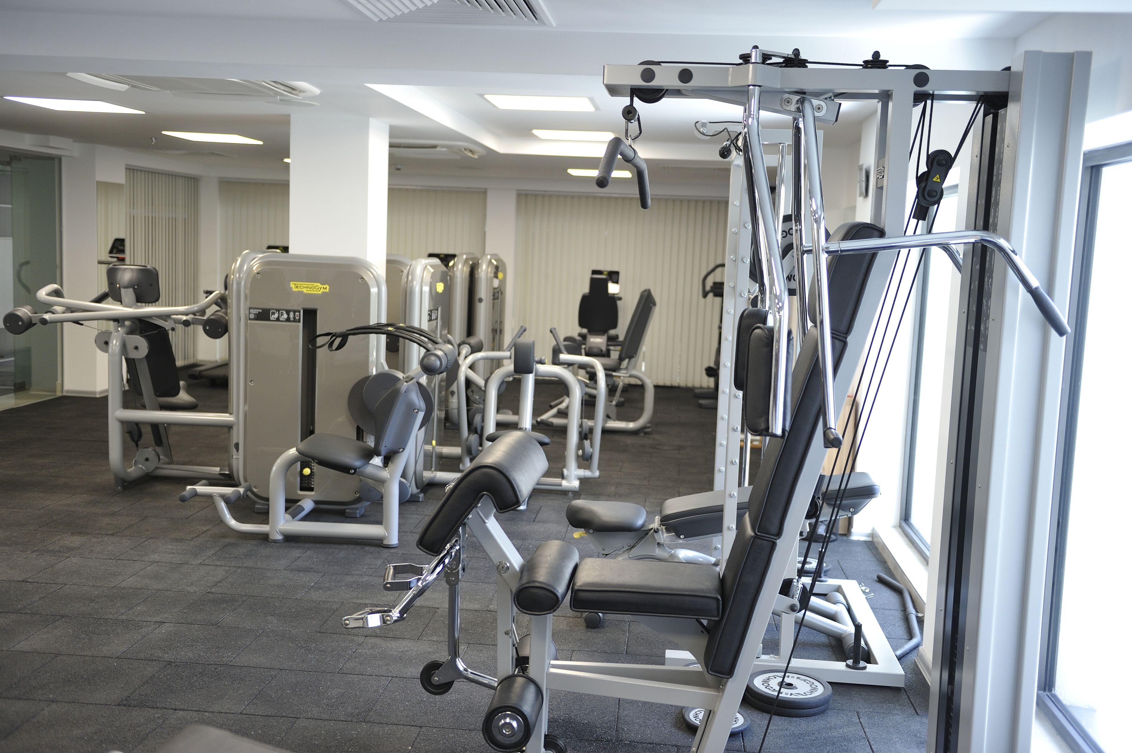 Un gimnasio con diferentes máquinas de ejercicio, una banca de pesas y una cinta de correr.