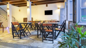 A dining area with tables and chairs, a staircase, and a television on the wall. - Hotel Villa Santo Antonio (Salvador)