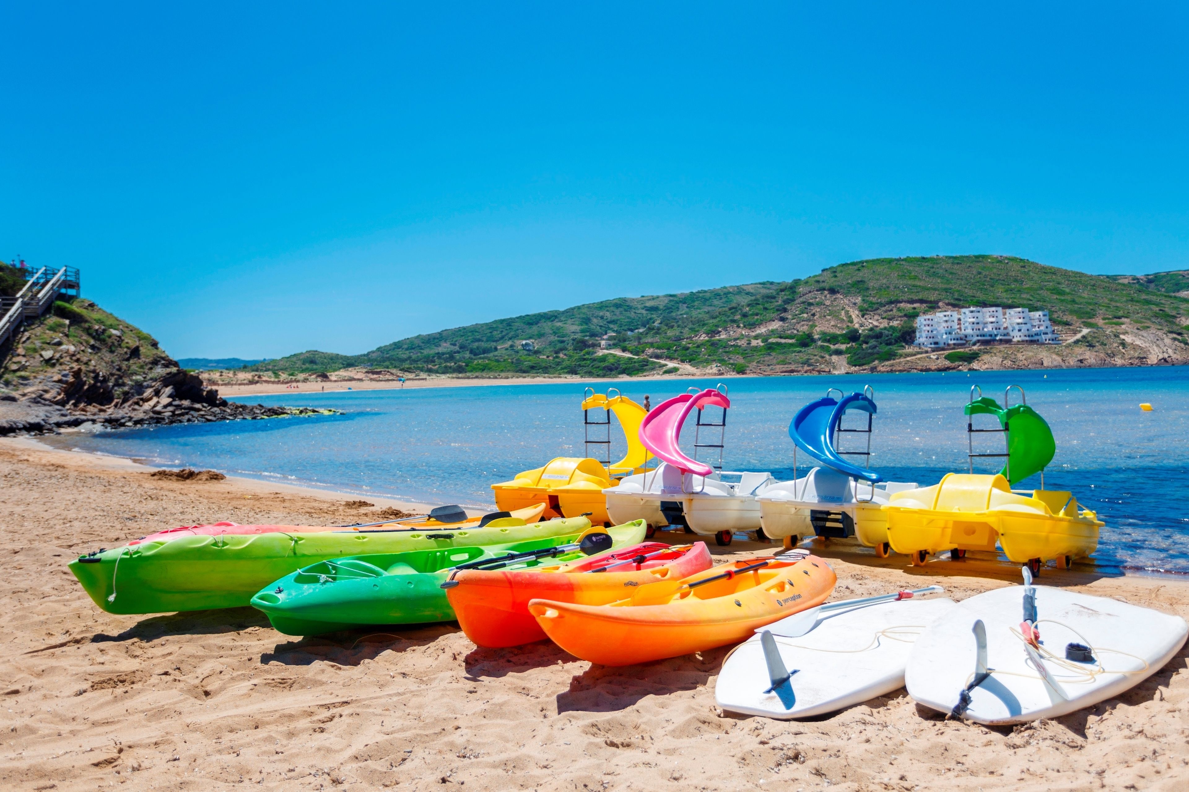 Una playa con kayaks de colores y una torre de salvavidas.