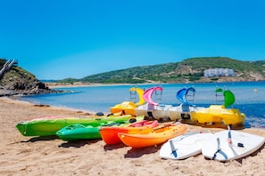 A beach with colorful kayaks and a lifeguard tower. - Carema Garden Village (Mercadal)